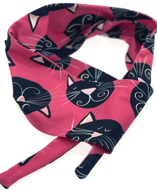 Virkkukoukkusen monikäyttöinen Lirpukkahuivi päähän, kaulaan tai vaikka vyöksi - kuosina mustat kissat pinkillä pohjalla.