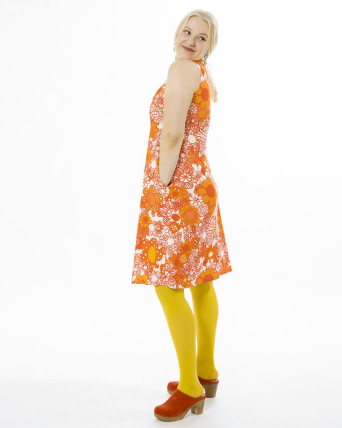 Kotimainen Virkkukoukkusen hihaton Helle-mekko U-pääntiellä. Aurinkoinen kelta-oranssi Maxikukkaralla-kuosi, jossa erikokoisia kukkia valkoisella raikastettuna.